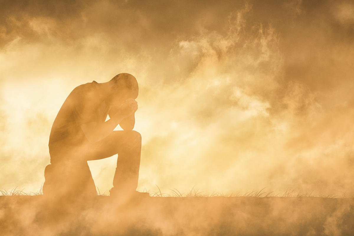 Farmer sitting in a dry field under financial and crop stress